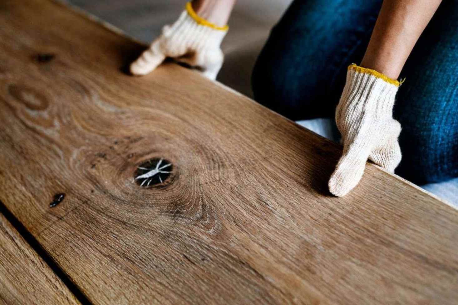 Should I Install Hardwood Floors Myself post img Tools and materials for installing wood flooring, including a hammer, utility knife, gloves, a red power drill, a black bucket with red spacers, and a floor leveling too.
